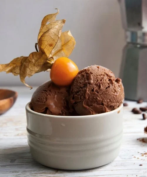 Helado de dos bolas de chocolate con un fruto de aguaymanto encima.