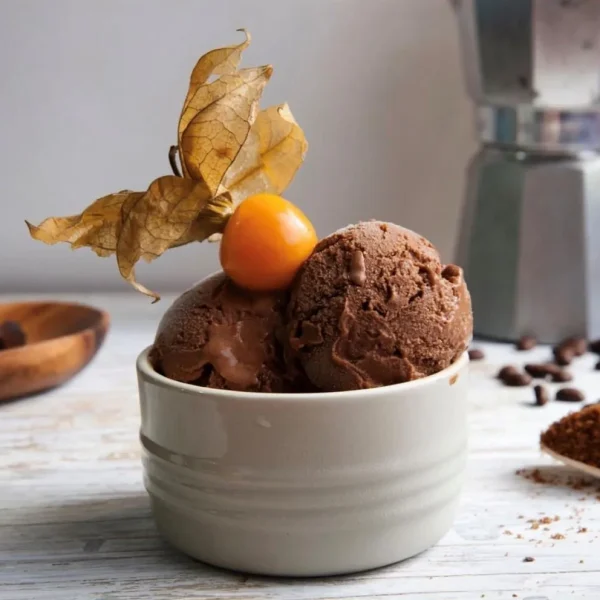 Helado de dos bolas de chocolate con un fruto de aguaymanto encima.